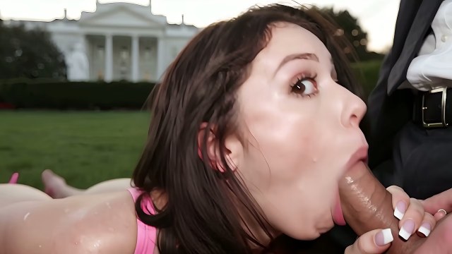 Short dark-haired woman in pink latex giving a close blowjob outdoors by a white neoclassical building